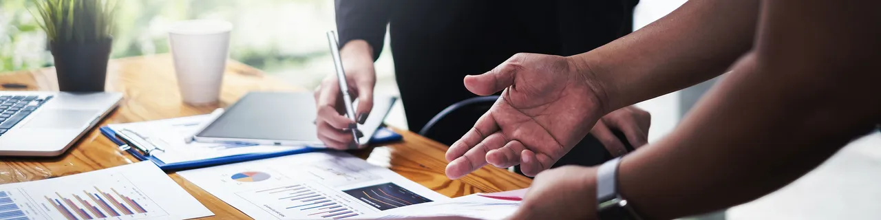 Handen wijzen naar een document op tafel. Handen wijzen naar een document op tafel.
