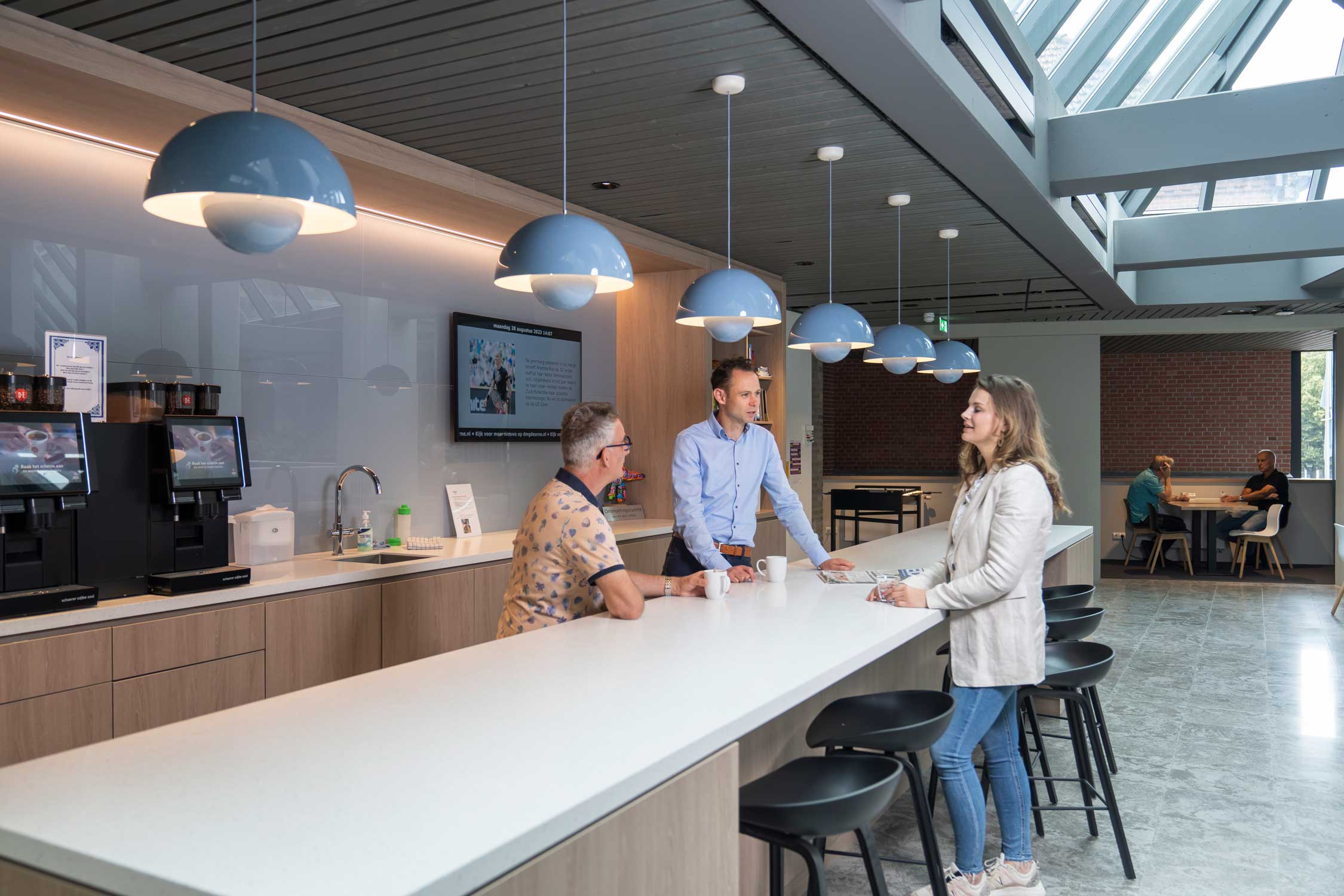 Drie personen in gesprek in de pantry onder het genot van een kopje koffie