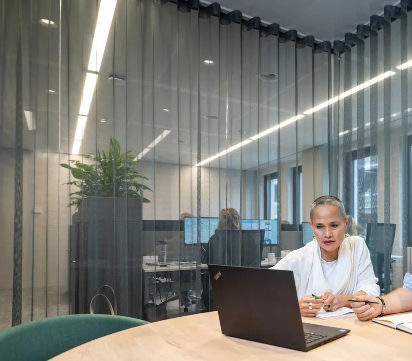 Een medewerker zit in een vergadering te overleggen en aantekeningen te maken, kijkend naar het sche Een medewerker zit in een vergadering te overleggen en aantekeningen te maken, kijkend naar het sche