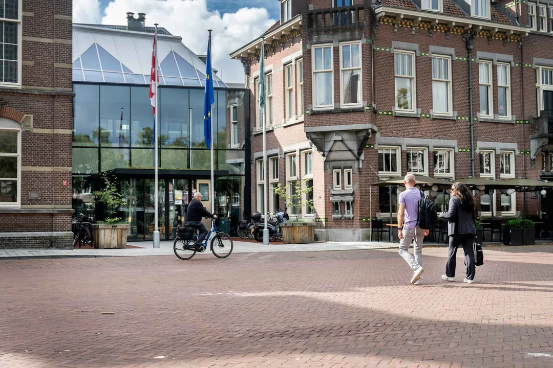 Twee personen lopen richting de hoofdingang van het Huis voor de Samenleving.