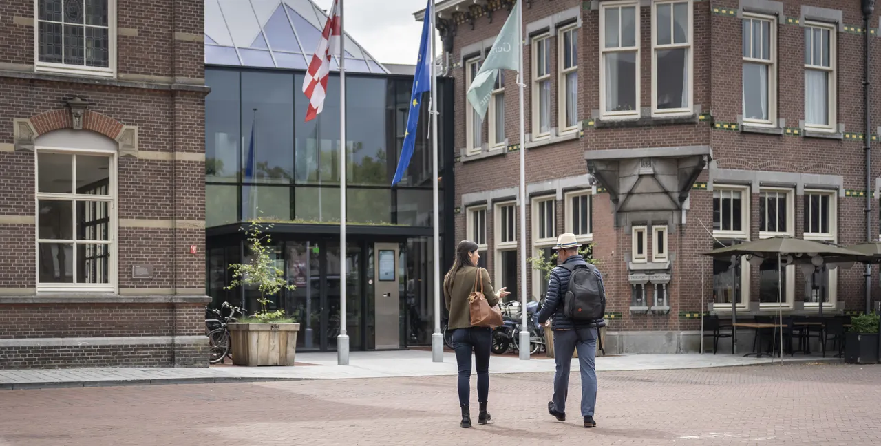 Twee personen lopen richting het Huis van de Samenleving.